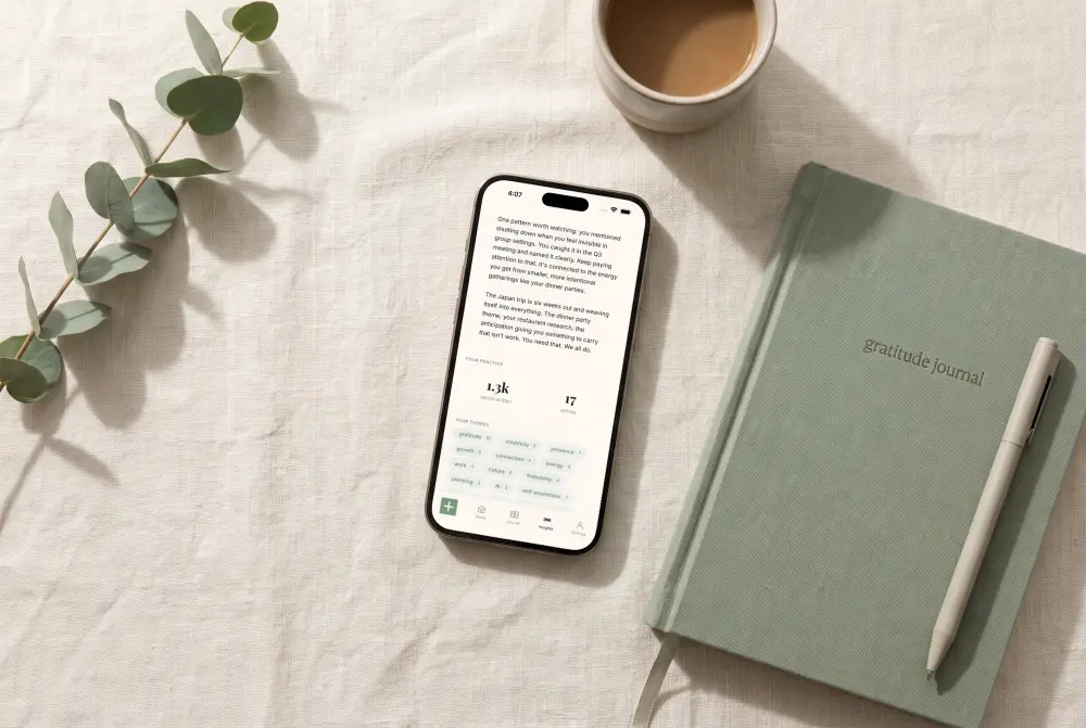 Already There Weekly Insights on an iPhone lying next to a paper gratitude journal and a cup of coffee